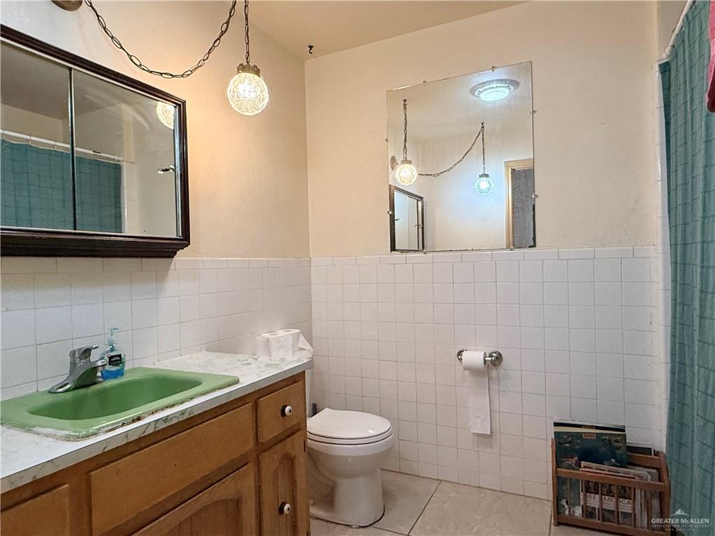 603 South Alamo Road Alamo, TX 78516 - Photo 9 of 17 a bathroom with a granite countertop sink a toilet and mirror