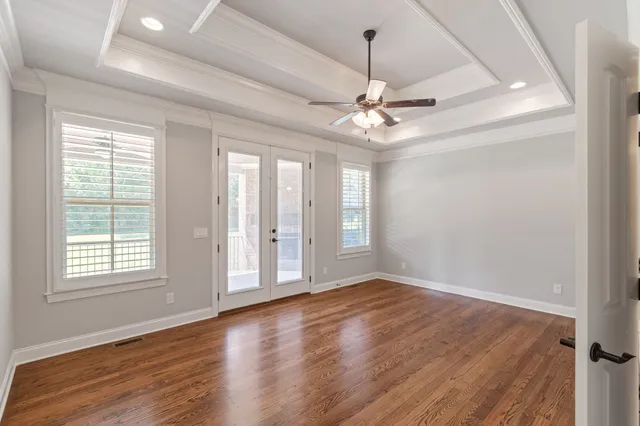 an empty room with a chandelier fan and windows