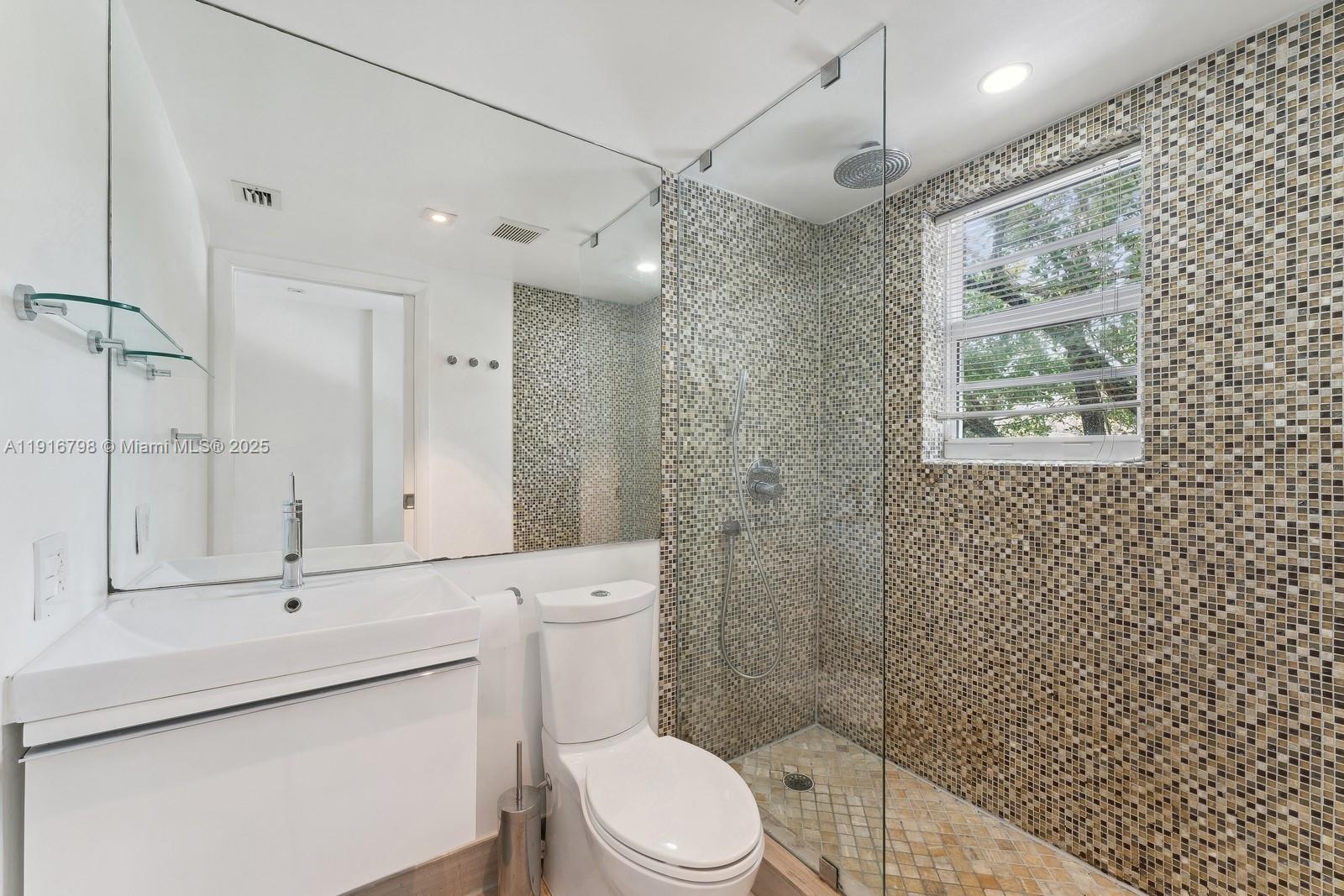 4812 Pine Tree Drive, Unit 206 Miami Beach, FL 33140 - Photo 11 of 14 a bathroom with a toilet a sink a shower and a mirror