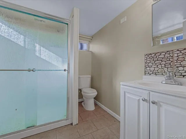 a bathroom with a granite countertop toilet a sink and a mirror