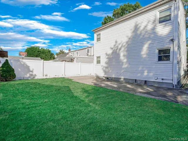 a view of backyard with barbeque grill potted plants and a big yard