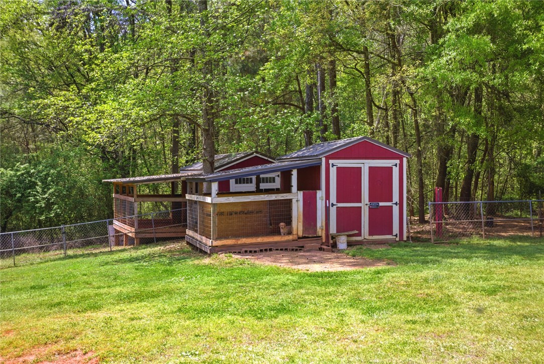 199 Williams Farm Road Westminster, SC 29693 - Photo 28 of 47 This outdoor space features a versatile shed with an attached, covered enclosure amidst a lush, treed backdrop.