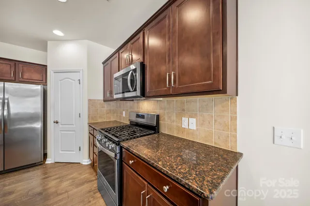 a kitchen with stainless steel appliances granite countertop a stove a refrigerator and a microwave