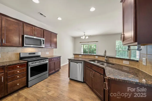 a kitchen with stainless steel appliances granite countertop a stove a sink and a microwave