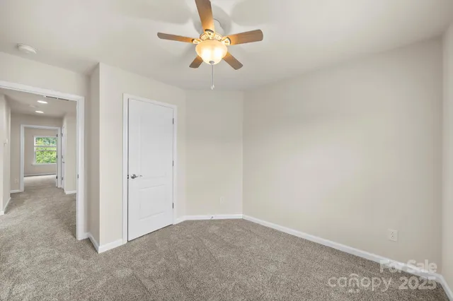 an empty room with chandelier fan and windows