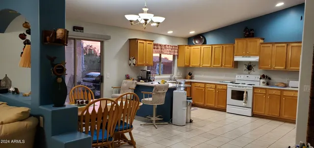 a kitchen with stainless steel appliances granite countertop a sink a stove top oven a dining table and chairs with wooden floor