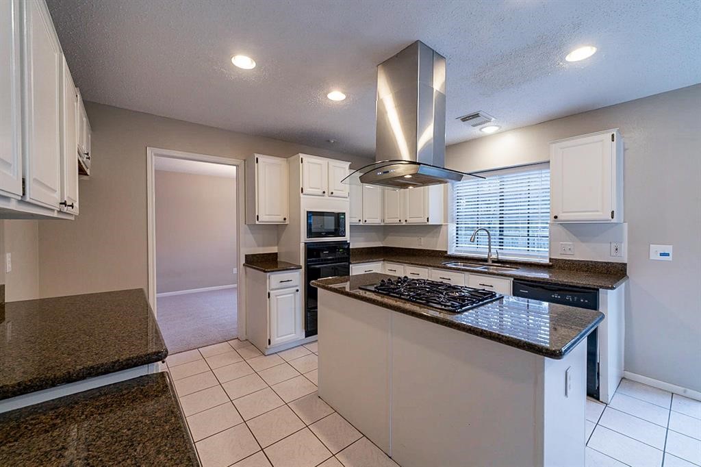 75 Breezy Point Place The Woodlands, TX 77381 - Photo 7 of 19 The kitchen has the island w gas cooktop, granite counters and white cabinetry.