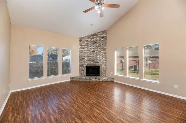 a view of an empty room with wooden floor and a fireplace