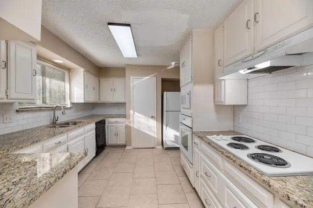 a kitchen with granite countertop a sink stove and refrigerator