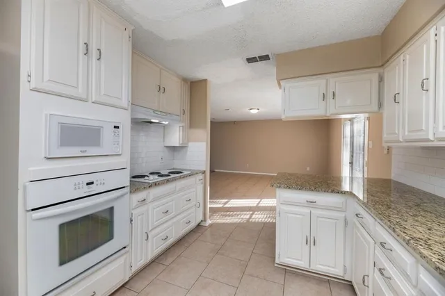 a kitchen with granite countertop white cabinets and stainless steel appliances