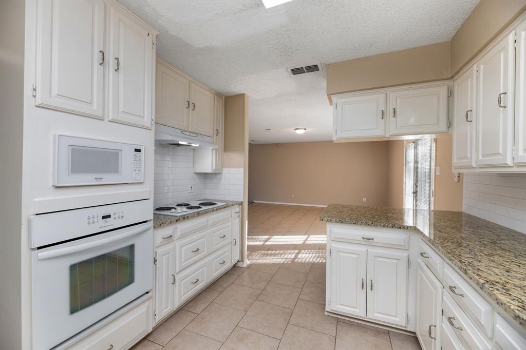2317 Jenson Circle Fort Worth, TX 76112 - Photo 9 of 21 a kitchen with granite countertop white cabinets and stainless steel appliances