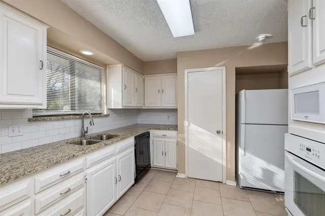 a kitchen with a sink dishwasher a refrigerator and cabinets