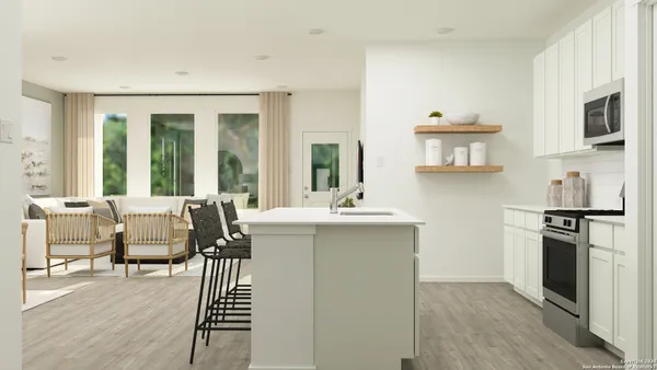 a living room with stainless steel appliances furniture a fireplace and a kitchen view