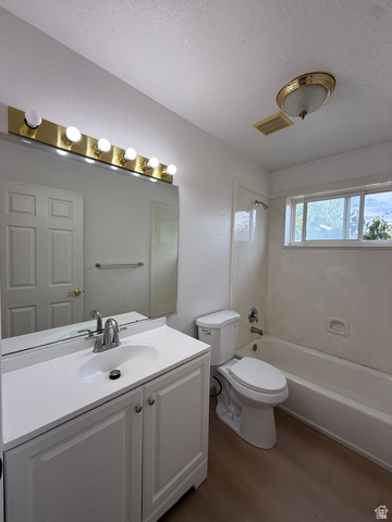 838 East Mountain Road Logan, UT 84321 - Photo 23 of 37 Full bathroom featuring a single white vanity with an integrated sink, a large mirror, a toilet, a full bathtub with a shower, and wood-finish flooring