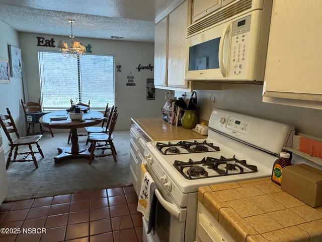 a kitchen with a stove a refrigerator and chairs