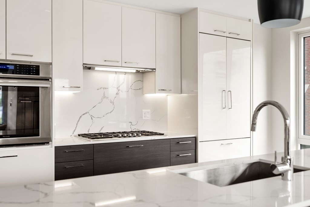 110 Broad Street, Unit 401 Boston, MA 02110 - Photo 2 of 24 a living room with stainless steel appliances kitchen island granite countertop a refrigerator and a stove top oven