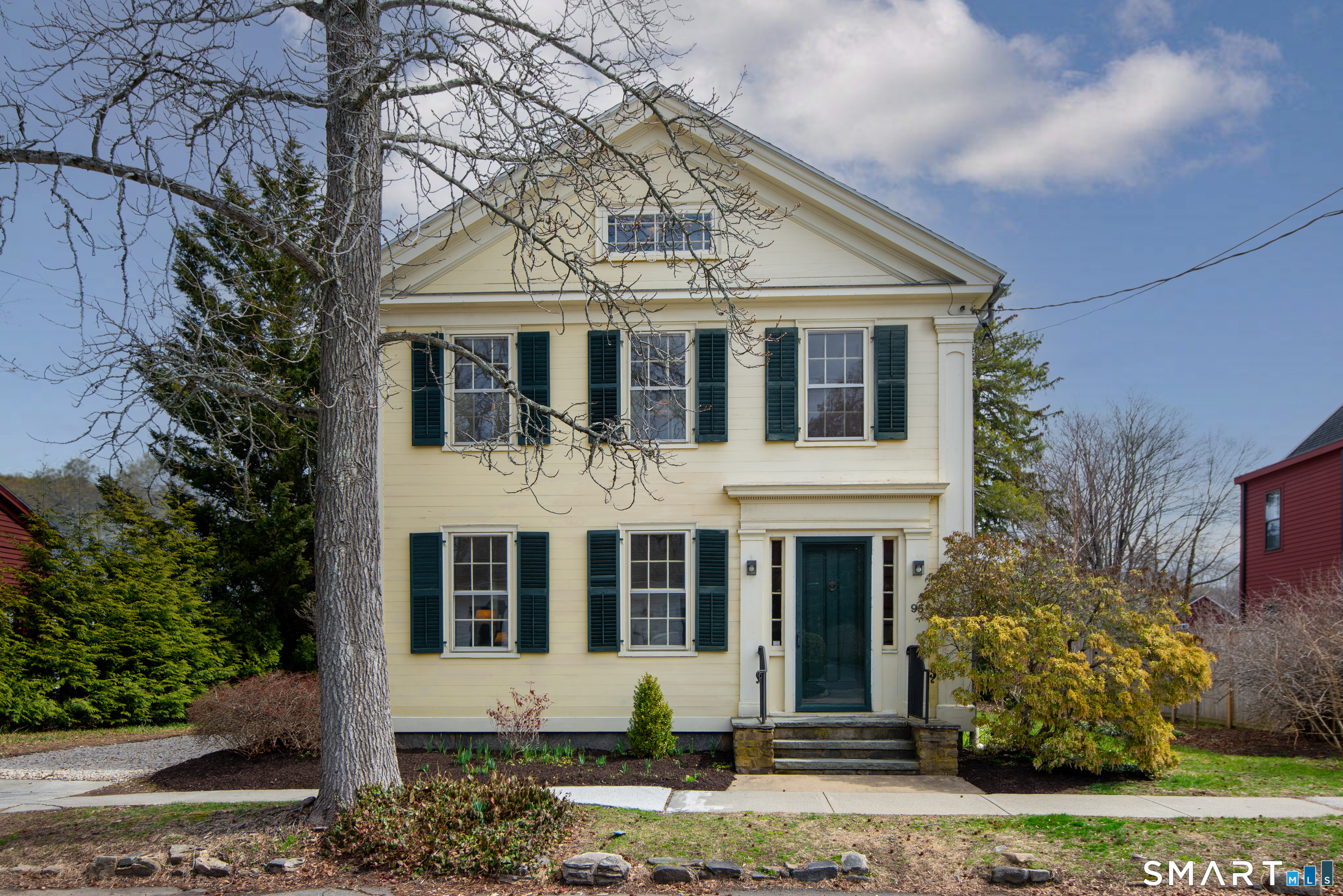 a view of a white house with large windows and a small yard