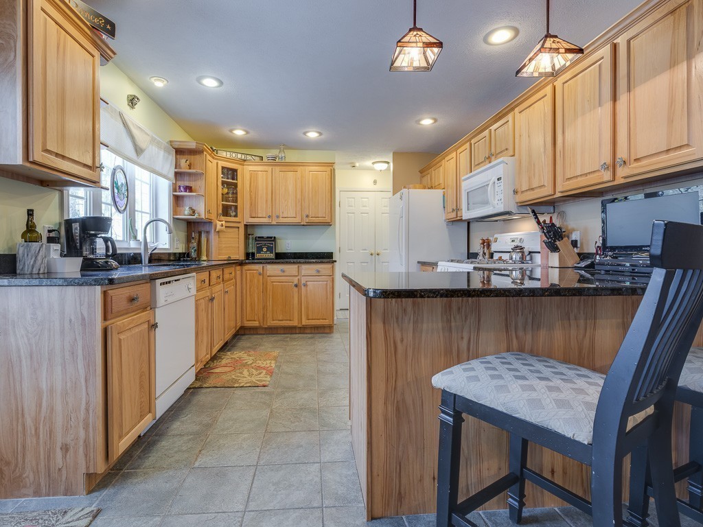 58 Mixter Road Holden, MA 01520 - Photo 11 of 30 a kitchen with stainless steel appliances granite countertop a table chairs sink refrigerator and cabinets