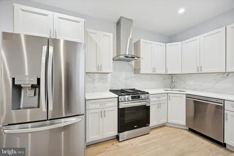 a kitchen with stainless steel appliances white cabinets and wooden floor