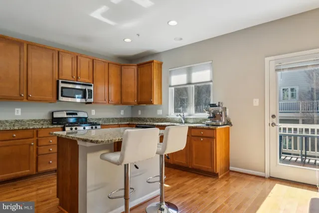 a kitchen with stainless steel appliances granite countertop a stove a sink dishwasher and a microwave oven with wooden floor