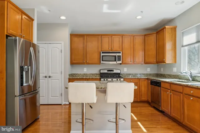 a kitchen with stainless steel appliances granite countertop a refrigerator a stove a sink a dining table and chairs