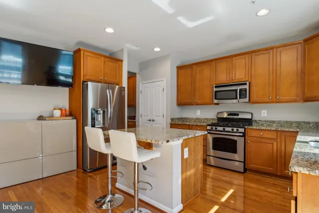 a kitchen with stainless steel appliances granite countertop a stove top oven a sink dishwasher a dining table and chairs with wooden floor