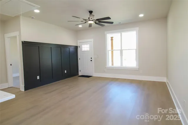 a kitchen with stainless steel appliances kitchen island granite countertop a refrigerator a sink dishwasher a stove and white cabinets with wooden floor