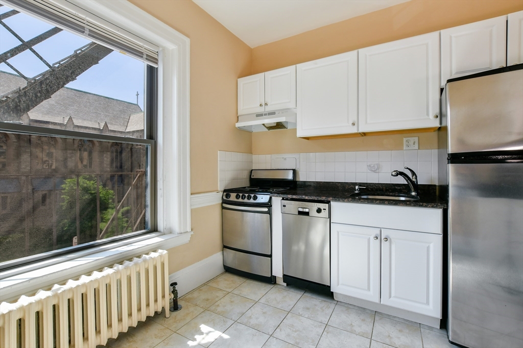 1091 Boylston Street, Unit 31 Boston, MA 02215 - Photo 9 of 14 a kitchen with white cabinets a sink and a stove