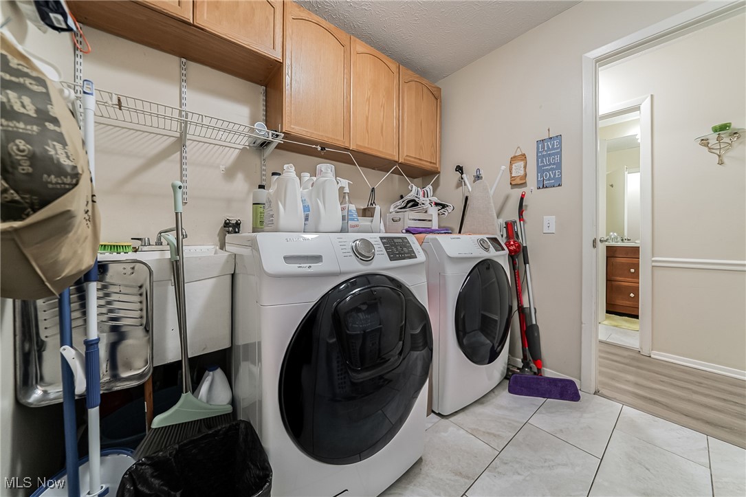 10794 Waterfall Road Strongsville, OH 44149 - Photo 28 of 37 Laundry room featuring cabinet space, light tile patterned floors, a textured ceiling, and washing machine and dryer