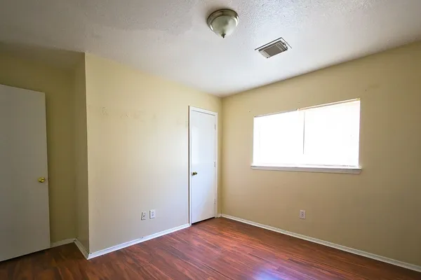 an empty room with wooden floor and windows