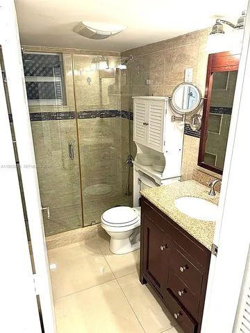 a bathroom with a granite countertop toilet sink and mirror
