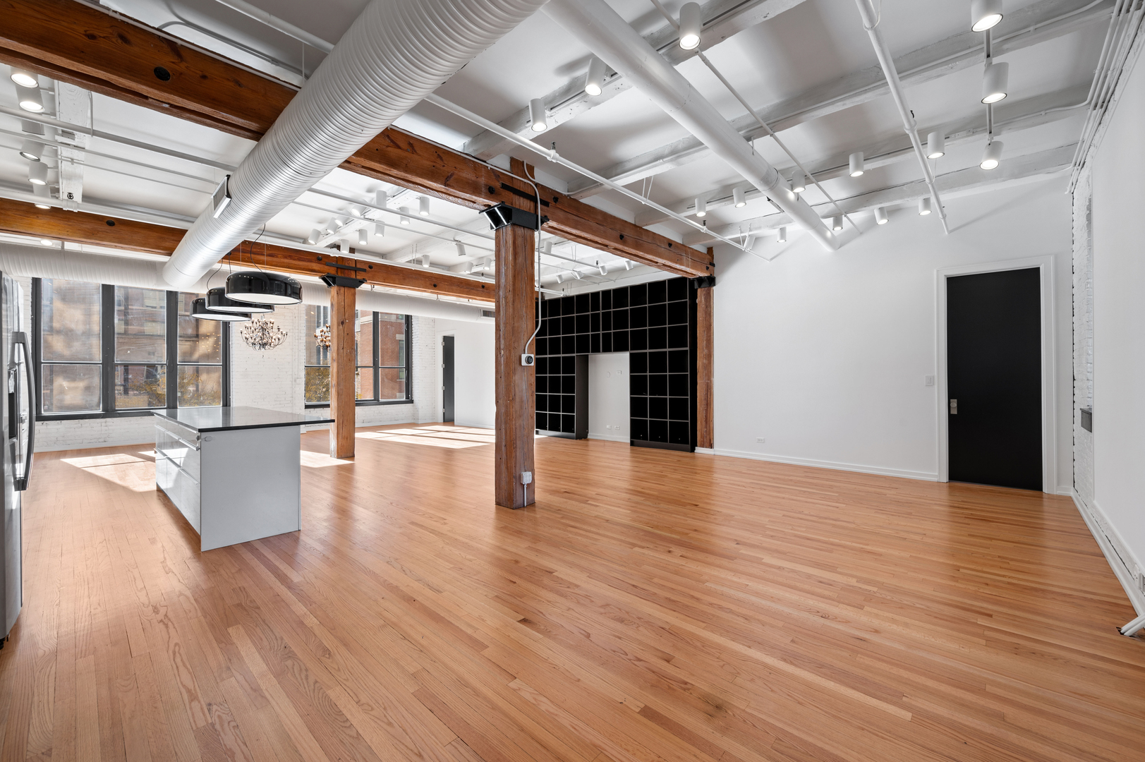 900 West Jackson Boulevard, Unit 3W Chicago, IL 60607 - Photo 6 of 38 a view of an empty room with wooden floor and a kitchen