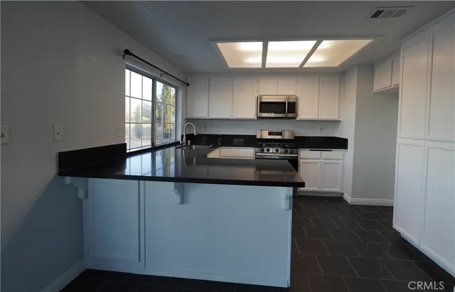a kitchen with granite countertop a sink a stove and cabinets
