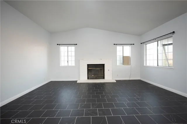 a view of an empty room with a window and fireplace