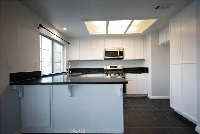 a kitchen with kitchen island granite countertop a sink appliances cabinets and a counter top space