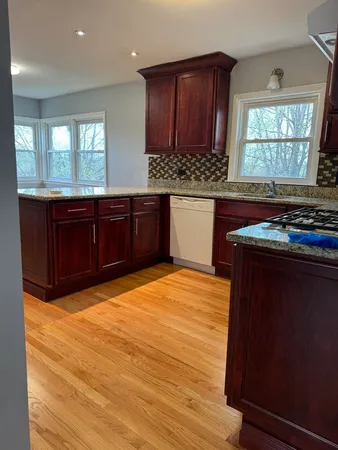 a kitchen with stainless steel appliances granite countertop wooden cabinets a stove a sink and a window