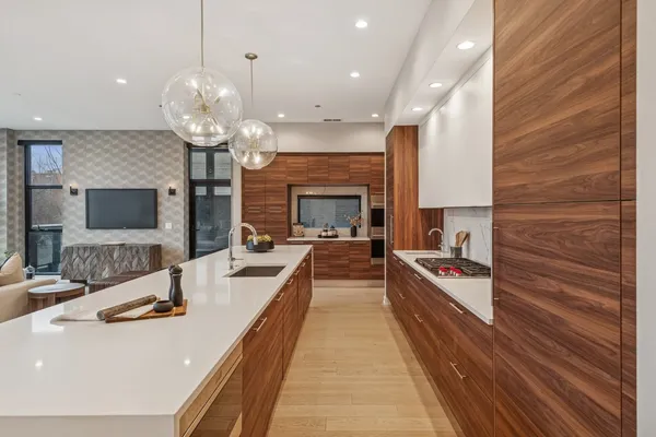 a large kitchen with stainless steel appliances a large counter top a fireplace and a chandelier