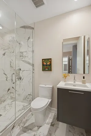 a bathroom with a toilet a sink a mirror a shower a window and vanity