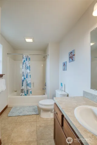 a bathroom with a granite countertop sink a toilet a mirror and bathtub