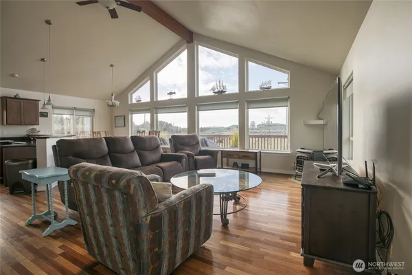 a living room with furniture large windows and wooden floor
