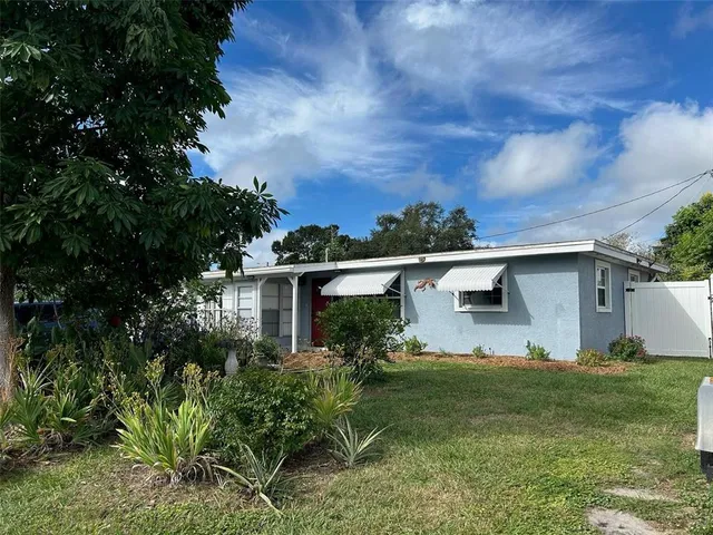 a view of a yard in front of a house with a large tree