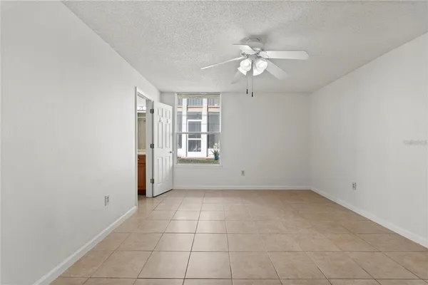 an empty room with a chandelier fan and windows
