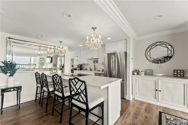 a kitchen with kitchen island granite countertop a dining table chairs cabinets and stainless steel appliances