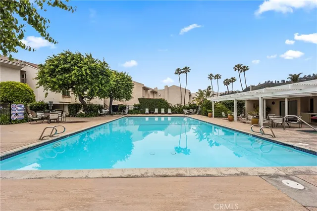 a view of a swimming pool with lawn chairs and plants