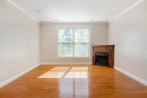 a view of empty room with wooden floor and fireplace