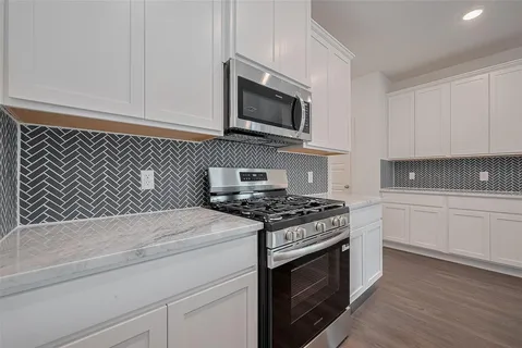 a kitchen with stainless steel appliances granite countertop white cabinets a stove top oven and sink