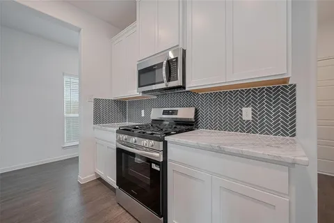 a kitchen with stainless steel appliances granite countertop a stove a microwave and a white cabinets
