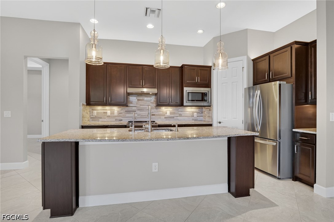 12804 Epping Way Fort Myers, FL 33913 - Photo 10 of 40 a kitchen with stainless steel appliances granite countertop a refrigerator a stove a sink and a microwave