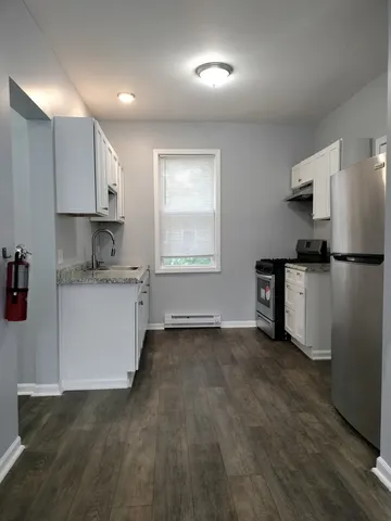a view of a kitchen with a sink and dishwasher stove top oven with wooden floor