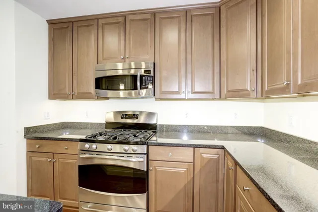 a kitchen with granite countertop cabinets stainless steel appliances and a sink